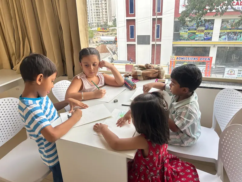 Children drawing at a table by a large window in an art class at Ekreeti Creatives